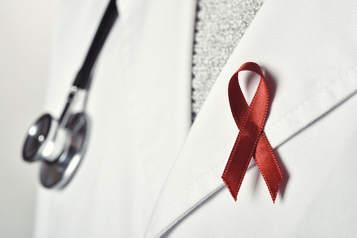 A doctor wearing a red ribbon on the lapel.